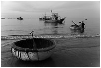 Coracle and fishing boats at dawn. Mui Ne, Vietnam (black and white)