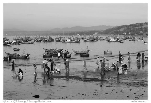 Hawkers gather on mirror-like beach in early morning. Mui Ne, Vietnam