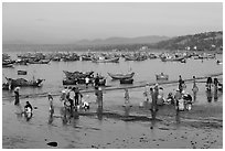 Hawkers gather on mirror-like beach in early morning. Mui Ne, Vietnam (black and white)