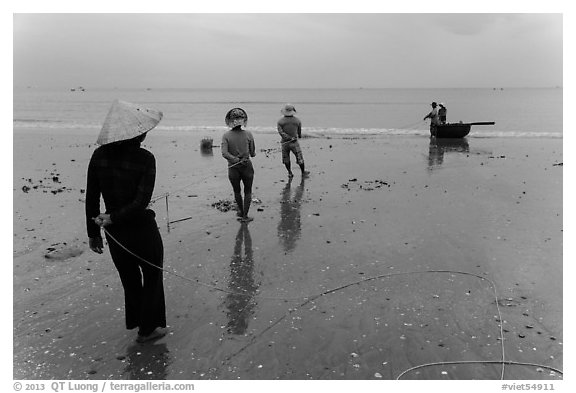 Fishermen pulling line onto beach. Mui Ne, Vietnam