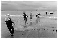 Fishermen lining up to pull net onto beach. Mui Ne, Vietnam (black and white)