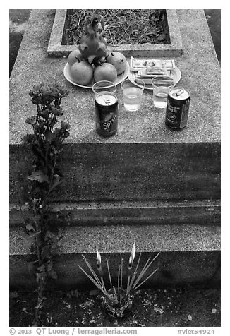 Grave with offerings of incense, flowers, drinks, fruit, and fake money. Ben Tre, Vietnam (black and white)