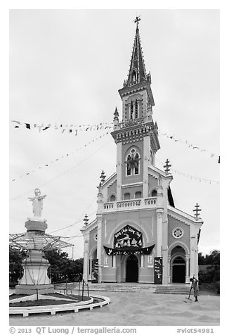 Man drying rice hulls in front of church. Tra Vinh, Vietnam