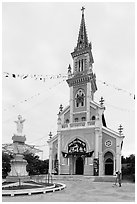 Man drying rice hulls in front of church. Tra Vinh, Vietnam (black and white)