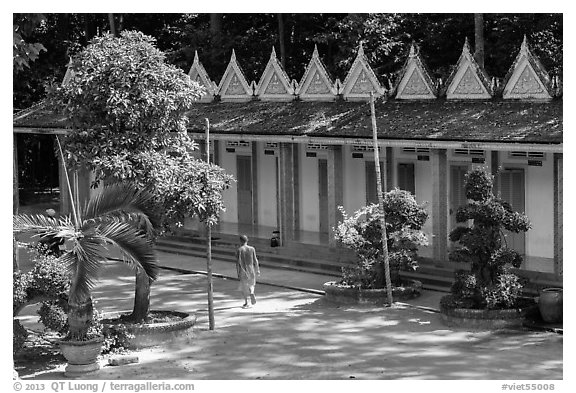 Monk walking past huts, Hang Pagoda. Tra Vinh, Vietnam