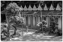 Monk walking past huts, Hang Pagoda. Tra Vinh, Vietnam ( black and white)