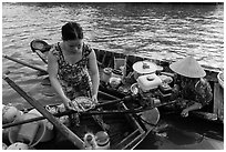 Woman gets bowl of noodles from floating market. Can Tho, Vietnam (black and white)