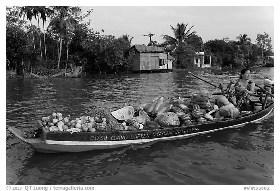 Woman with boat loaded with produce eating noodles. Can Tho, Vietnam (black and white)