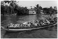 Woman with boat loaded with produce eating noodles. Can Tho, Vietnam ( black and white)
