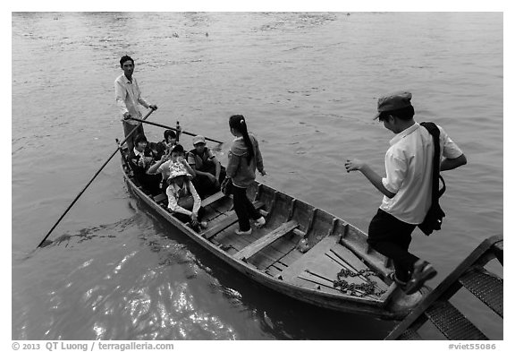 Schoolchildren stepping onto boat. Can Tho, Vietnam (black and white)