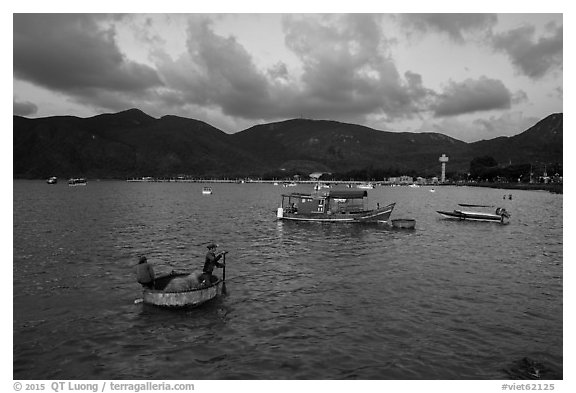 Men in coracle boat paddling in Con Son harbor. Con Dao Islands, Vietnam (black and white)