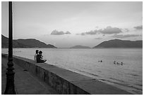 Young women sitting on seawall, evening, Con Son. Con Dao Islands, Vietnam ( black and white)
