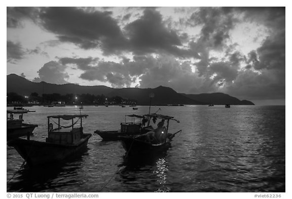 Men with light on fishing boat at dawn, Con Son harbor. Con Dao Islands, Vietnam (black and white)