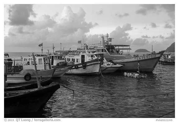 Fishing boats and man standing on raft, early morning, Con Son harbor. Con Dao Islands, Vietnam (black and white)