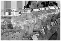 Woman peering over row of eddible birds nest jars. Con Dao Islands, Vietnam ( black and white)