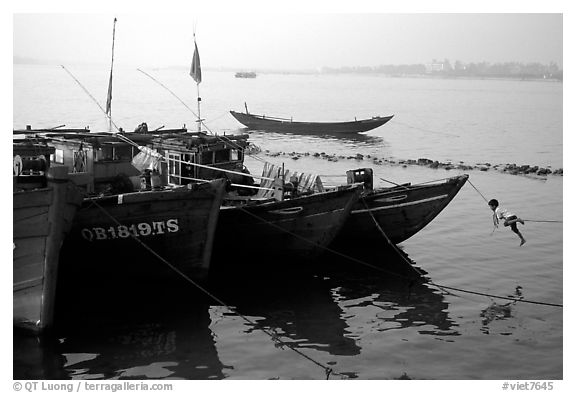 Children climbing aboard Fishing boat, Dong Hoi. Vietnam (black and white)