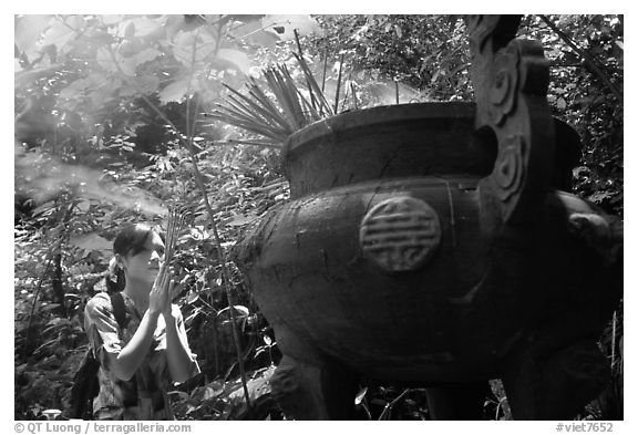Tourist praying at an urn with incense near the entrance of Phong Nha Cave. Vietnam (black and white)