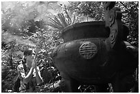 Tourist praying at an urn with incense near the entrance of Phong Nha Cave. Vietnam ( black and white)