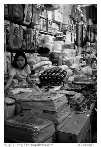 Vendor sitting amongst Abondance of cheap goods imported from nearby China at the Dong Kinh Market. Lang Son, Northest Vietnam (black and white)