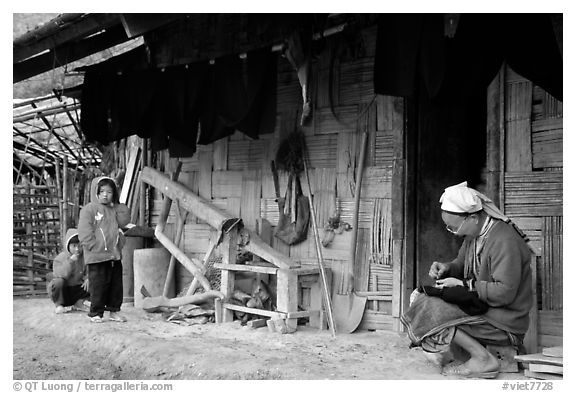 Elderly woman sewing  on her doorstep as kids look up. Northeast Vietnam (black and white)