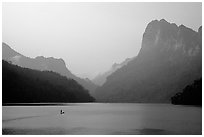 Dugout boat in Ba Be Lake, surrounded by tall cliffs, early morning. Northeast Vietnam ( black and white)