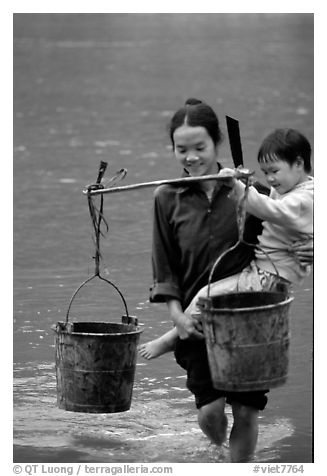 Woman of the Tay minority carrying crossing the river with child, Ba Be Lake. Vietnam (black and white)