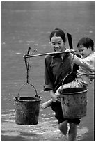 Woman of the Tay minority carrying crossing the river with child, Ba Be Lake. Vietnam (black and white)