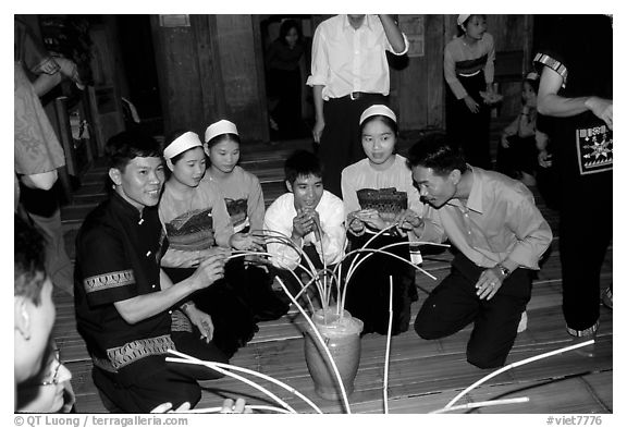 Thai women and guests drinking rau can alcohol with long straws, Ban Lac, Mai Chau. Northwest Vietnam