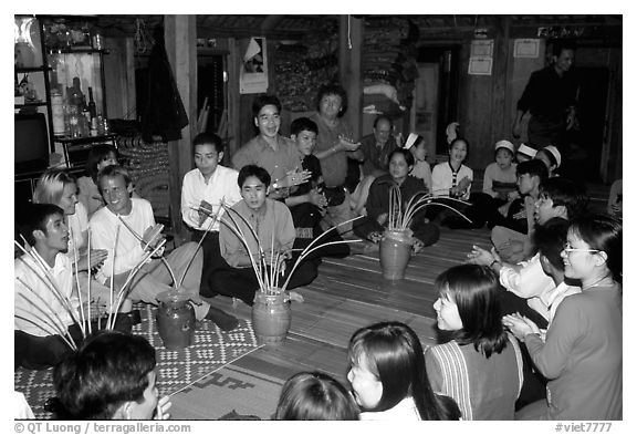 Guests in a thai house gather around jars of rau can alcohol, Ban Lac, Mai Chau. Northwest Vietnam (black and white)