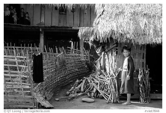 Woman in front of her hut and family on stilt house, between Lai Chau and Tam Duong. Northwest Vietnam