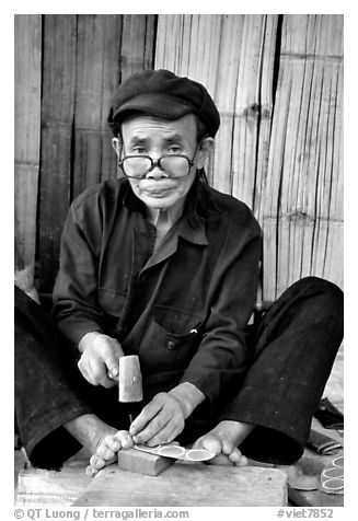 Black Dzao man making the decorative coins used in the children hats, between Tam Duong and Sapa. Northwest Vietnam