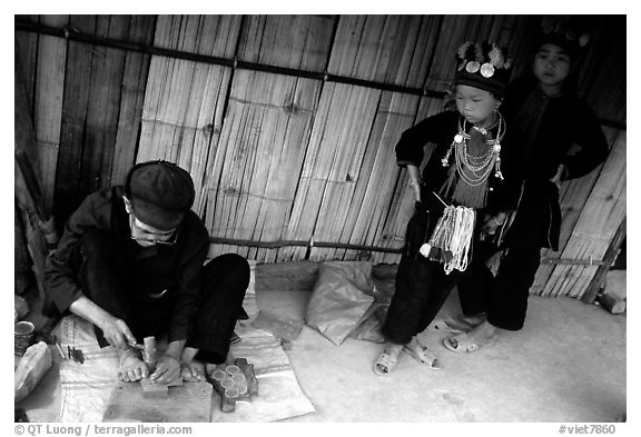 Black Dzao children look at a man  making the decorative coins used on their hats, between Tam Duong and Sapa. Northwest Vietnam (black and white)