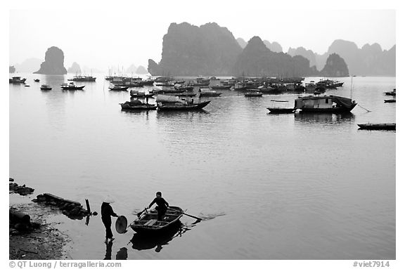 Rowboat meeting woman on shore. Halong Bay, Vietnam (black and white)
