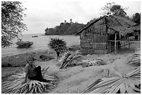 Woman taking a break sitting on leaves used to build a hut. Hong Chong Peninsula, Vietnam ( black and white)