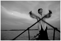 Boater using the X-shaped paddle characteristic of the Delta, sunset. Can Tho, Vietnam ( black and white)