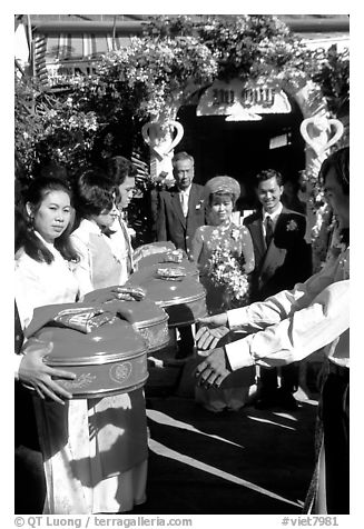 Gifts are exchanged as a newly wedded couple exits the bride's home. Ho Chi Minh City, Vietnam (black and white)