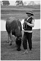 Boy wearing the Boi Doi military hat popular in the North, with water buffalo, near Ninh Binh. Vietnam ( black and white)