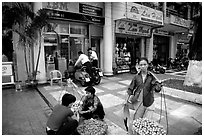 Old and new: street fruit vendors and computer store. Ho Chi Minh City, Vietnam ( black and white)