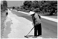 Rice being dried on sides of road. Mekong Delta, Vietnam (black and white)