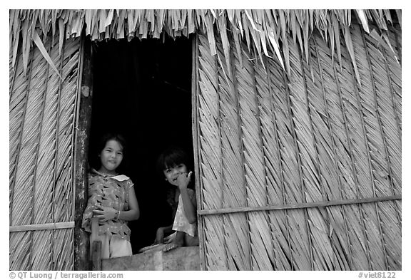 Children pear through a traditional hut. Hong Chong Peninsula, Vietnam