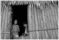 Children pear through a traditional hut. Hong Chong Peninsula, Vietnam (black and white)