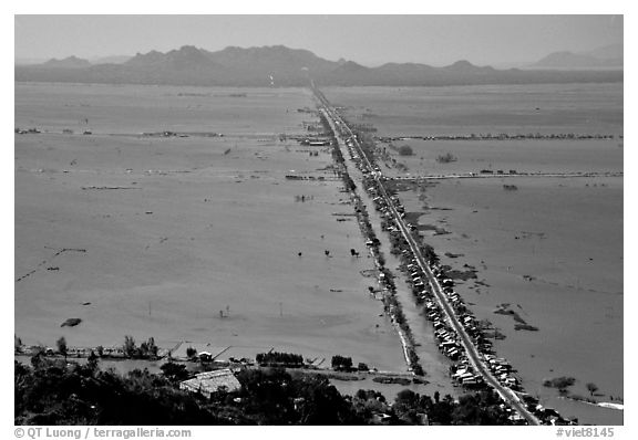 Stilts houses line a road traversing inundated rice fields, seen from Sam mountain. Cambodia is in the far. Chau Doc, Vietnam (black and white)