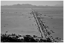 Stilts houses line a road traversing inundated rice fields, seen from Sam mountain. Cambodia is in the far. Chau Doc, Vietnam (black and white)