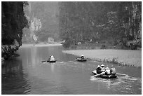 Villagers go to work floating a shallow river in Tam Coc. Ninh Binh,  Vietnam (black and white)