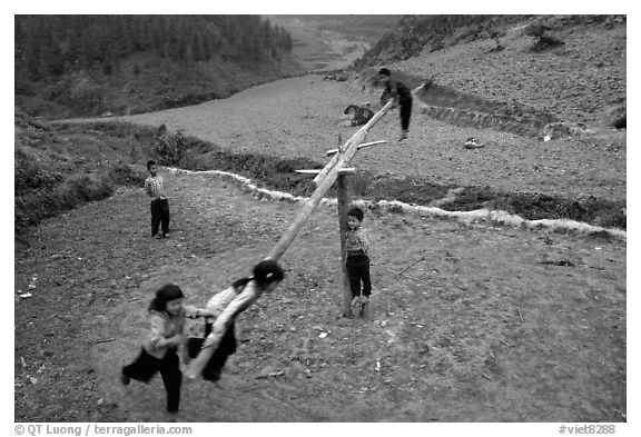 Children playing a rotating swing near Can Cau. Vietnam (black and white)