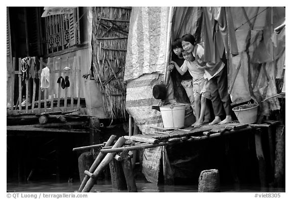 Children peering from their waterfront house. Can Tho, Vietnam (black and white)