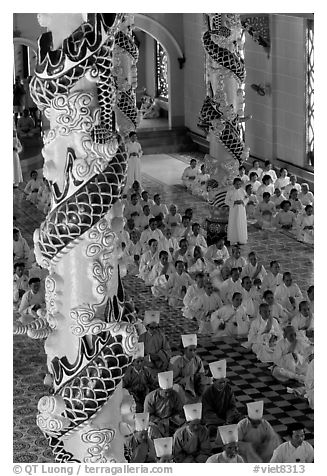 Priests and ornate columns inside the Great Caodai Temple. Tay Ninh, Vietnam