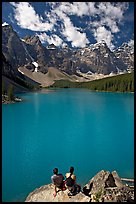 Couple sitting on the edge of Moraine Lake. Banff National Park, Canadian Rockies, Alberta, Canada (color)