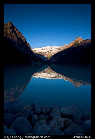 Boulders, Mirror-like Lake Louise and Victoria Peak, early morning. Banff National Park, Canadian Rockies, Alberta, Canada