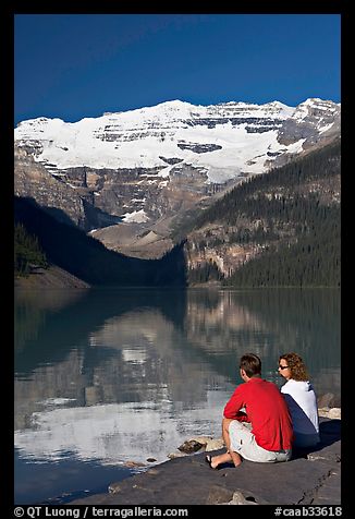 Couple sitting in the sun in front of Lake Louise, morning. Banff National Park, Canadian Rockies, Alberta, Canada